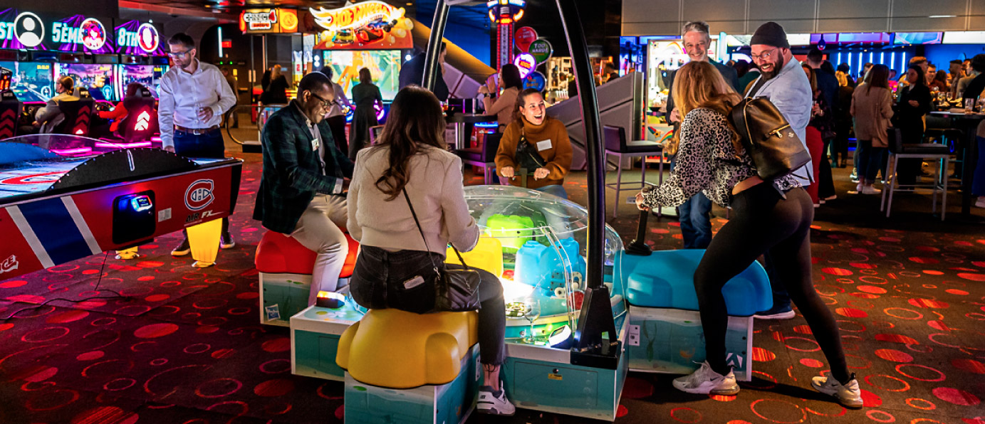 A group of people playing an interactive arcade game in a vibrant, colorful environment filled with neon lights and other games in the background.